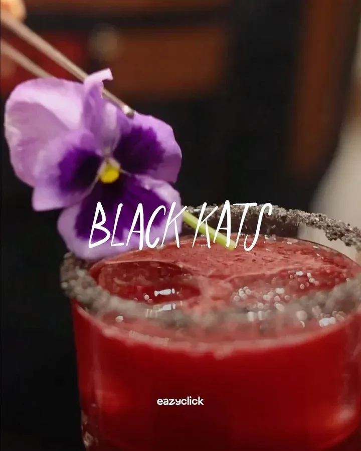 Cocktail rouge décoré d'une fleur violette, pour la présentation du projet Black Kats